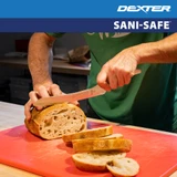 SANI-SAFE® Scalloped Offset Sandwich Knife cutting a load of bread on red cutting board