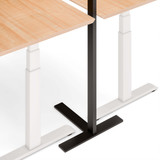 ofinto Stehlampe Lumino T-Standfuss unter Schreibtisch Elevate - Detailansicht der schwarzen Standfüsse mit Anti-Rutsch-Beschichtung unter höhenverstellbarem Bürotisch, platzsparende Integration von Beleuchtung und ergonomischem Arbeitsplatz