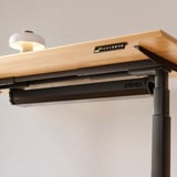 ofinto Kabelmanagement-System Schwarz geschlossen am höhenverstellbaren Schreibtisch Elevate - Detailaufnahme der weissen Kabelwanne unter FSC-zertifizierter Holztischplatte