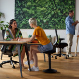 ofinto Move Sitz-Stehhocker im modernen Büro - flexible Arbeitsplatzgestaltung mit höhenverstellbaren Tischen und ergonomischen Bürostühlen für produktive Meetings