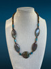 Front view of the Canyon Echo necklace displayed on a linen jewelry bust, featuring Blue Line Jasper, Apatite, and Tiger’s Eye gemstones. The handcrafted 20-inch artisan design showcases rich blue and earthy brown tones, created by Stone & Story Jewelry.