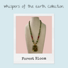Forest Bloom Necklace from the Whispers of the Earth Collection — a handcrafted gemstone necklace featuring a wire-wrapped Unakite pendant with green Kambaba Jasper and deep red Malaysian Jade beads, accented with golden details and a floral clasp on a neutral display bust