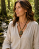 Model wearing the Forest Bloom handcrafted Unakite pendant necklace with Kambaba Jasper and Red Malaysian Jade beside a peaceful forest stream.