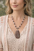 Woman wearing Blush of the Earth handcrafted rose quartz and smoky quartz necklace featuring natural leopard skin jasper pendant from Whispers of the Earth Collection.