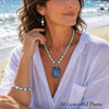Woman wearing the Ocean Current handcrafted necklace by Stone & Story featuring luminous glass pearls, blue agate spacers, and a Murano-inspired glass pendant.