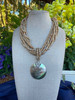 Driftwood & Shell Vintage Curated necklace displayed outdoors, highlighting natural coconut shell beads and a shimmering mother-of-pearl shell pendant.