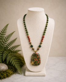 Forest Bloom artisan necklace displayed on a white jewelry bust with Unakite pendant wrapped in gold-tone wire, Kambaba Jasper, Red Malaysian Jade, and botanical forest-inspired styling.
