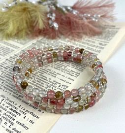 Cherry quartz memory wire bracelet with four layered pink and clear gemstone wraps displayed on open book background showing artisan craftsmanship