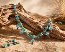 Desert Rain handcrafted necklace featuring turquoise and blue apatite chips, copper-colored freshwater pearls, and sparkling aqua crystal drops displayed on sunlit desert driftwood.