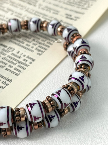 Buddha meditation memory wire bracelet with artisan glass beads and copper spacers displayed on open book background