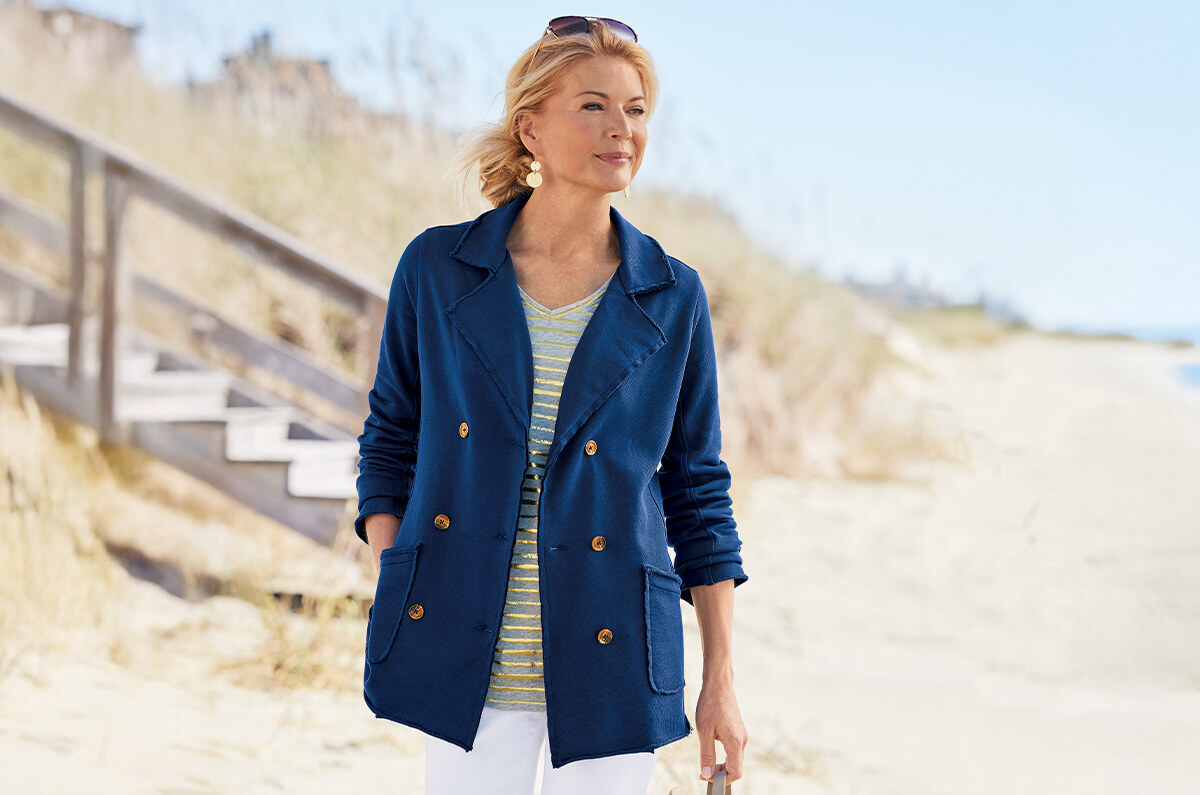 Image of woman walking down the beach wearing the blue Glennette French Terry Jacket
