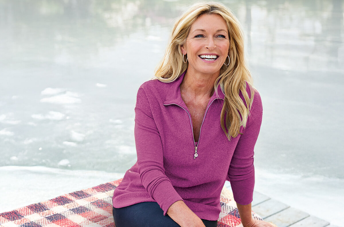 Image of a woman sitting by an icy lake wearing the warm purple Adalyn Pullover Tunic