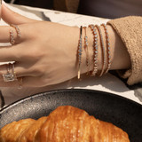 Hand on table wearing five gold bracelets