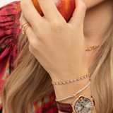 Hand holding a peach wearing three pave rings on her ring finger