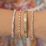 Wrist wearing four braclets with a mix cut diamond tennis bracelet