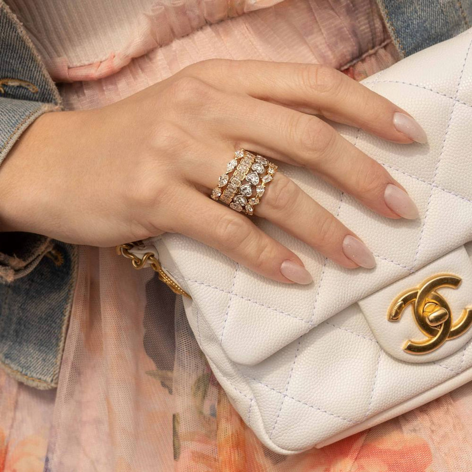 Hand holding a white bag, with four rings on her ring finger