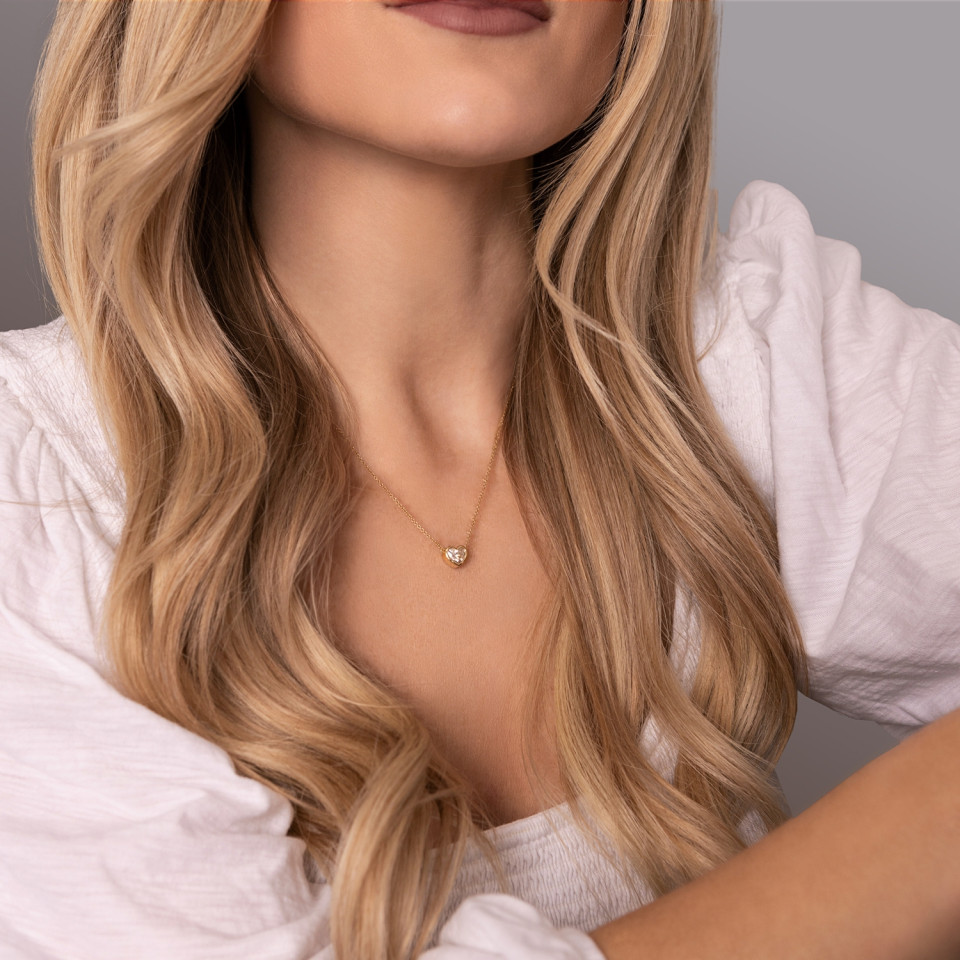 Woman wearing heart diamond necklace with blond curly hair