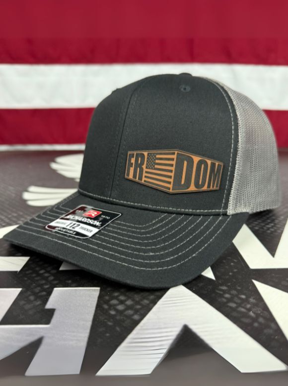 FREEDOM Flag Hat with laser-etched leather patch and mesh back on outdoor rock background