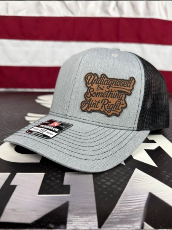 Undiagnosed But Something Aint Right hat with laser-engraved leather patch on Richardson 112 trucker cap