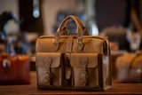 High quality light brown flight bag leather briefcase at an angle to show the sizing better. Made by Saddleback