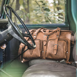 High quality lifestyle interior truck view of Saddleback Leather's Deep Pocket Leather Duffle Bag in Tan Brown / tan
