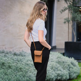 High quality tan colored leather walkers pouch on a female model outside. Made by Saddleback