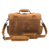 This is the back pf the tan full grain leather briefcase with the shoulder strap laying down in front of it.