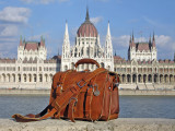 High quality red brown full grain leather briefcase in front of parliament in Budapest, Hungary.