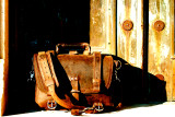 This is a red brown full grain leather briefcase in front of a wooden door.