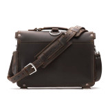 High quality back of a dark brown slim leather briefcase that has a strap laying in front of it.