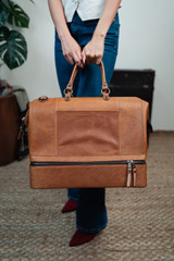 High quality lifestyle image of our tan compartment leather duffle