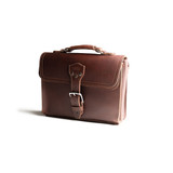 High quality front side of a red brown leather satchel with a front pocket angled.