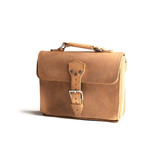High quality front side of a tan brown leather satchel with a front pocket.