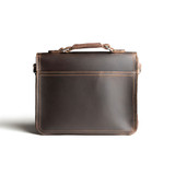High quality back side of a dark brown leather satchel with a front pocket.