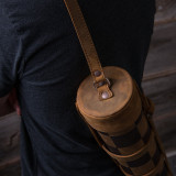 High quality top of a leather travel chess set that is rolled up with a shoulder strap over the shoulder.