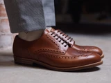 High quality natural tan full grain leather wing tip shoe side profile on foot with cuffed trousers - Saddleback Leather