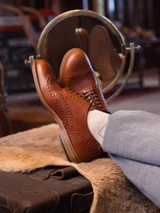 High quality natural tan full grain leather wing tip shoe three-quarter on-foot close-up with cuffed trousers - Saddleback Leather