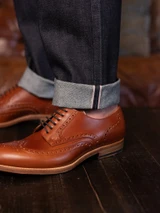 High quality natural tan full grain leather wing tip shoes studio three-quarter view on a wooden surface - Saddleback Leather
