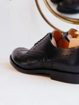 High quality close-up of black full grain leather wing tip shoe heel cup, ankle opening, and quarter brogue stitching - Saddleback Leather