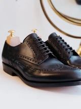 High quality black full grain leather wing tip shoes close-up side view of vamp, eyelets, and brogue styling - Saddleback Leather