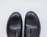High quality black full grain leather wing tip shoes overhead close-up of wing tip medallion and brogue perforations - Saddleback Leather