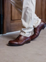 High quality dark oak full grain leather toe cap shoes standing three-quarter view on stone floor - Saddleback Leather