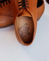 High quality tan full grain leather toe cap shoe interior detail showing stamped leather insole with brand logo - Saddleback Leather
