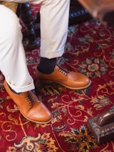 High quality tan full grain leather toe cap shoes top-down on-foot view on red Persian rug - Saddleback Leather