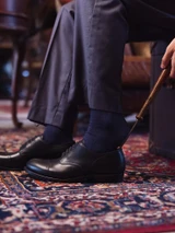 High quality black full grain leather toe cap shoe side angle with shoe horn showing heel and sole profile on oriental rug - Saddleback Leather