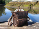 High quality this dark brown women's leather backpack is on a dock in Canada near Tofino and is showing the other angle.