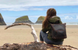 High quality this dark brown women's leather backpack is on Suzette's back at the beach in the sand.