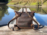 High quality this dark brown women's leather backpack is on a dock in Canada near Tofino and is showing the back.
