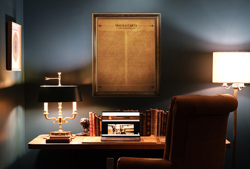 High quality framed copy of The Magna Carta burned into a large panel of aged looking tan leather hanging on an office wall.