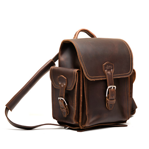 High quality dark brown full grain leather baby tank backpack from the front. 2 side pockets and shoulder pads on the straps for extra comfort. Made by Saddleback